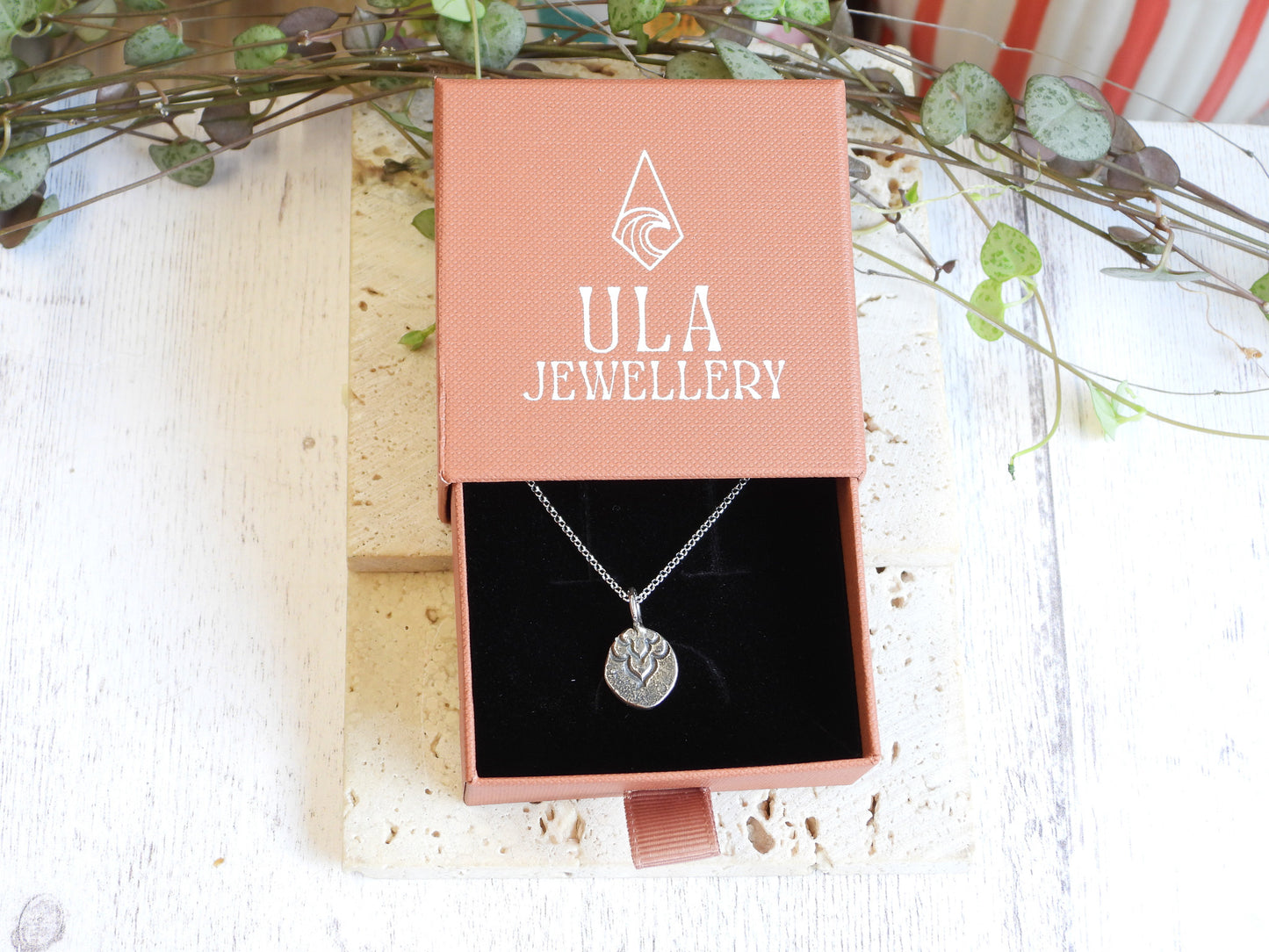 Silver necklace in a ULA Jewellery box with decorative branches in the background