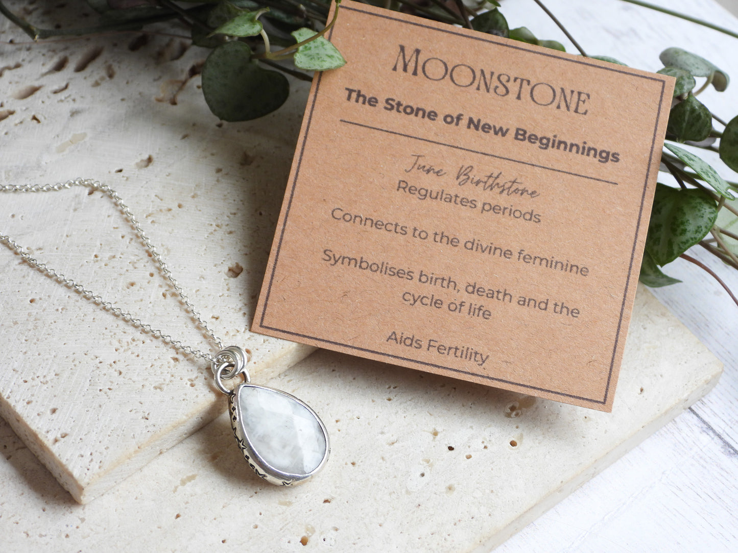 Moonstone necklace with descriptive card on a stone surface