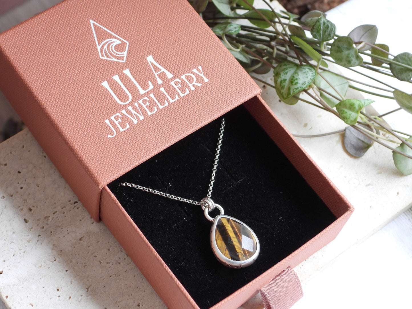 Jewelry box with a necklace featuring a teardrop-shaped pendant, branded 'ULA Jewellery'.