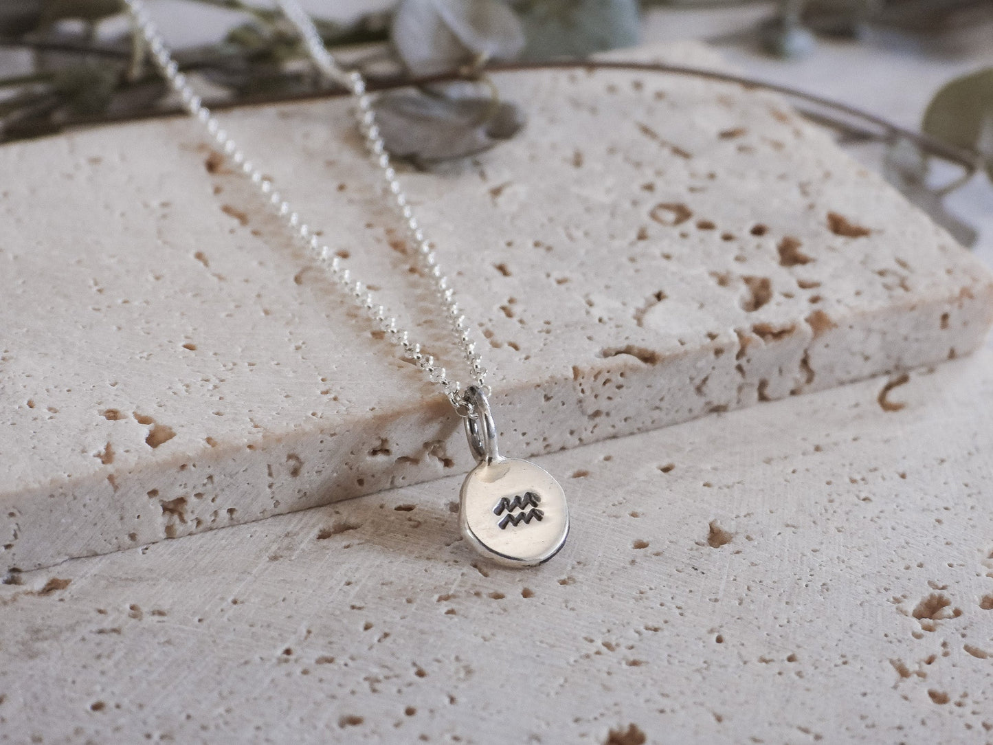 Silver necklace with a round pendant on a textured surface