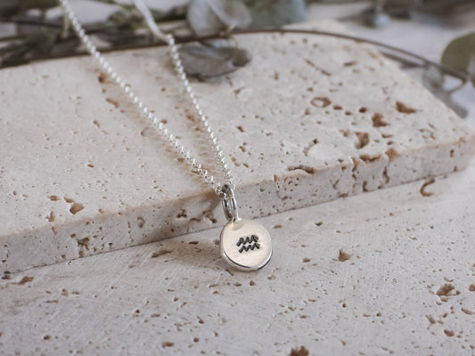 Silver necklace with a round pendant on a textured surface