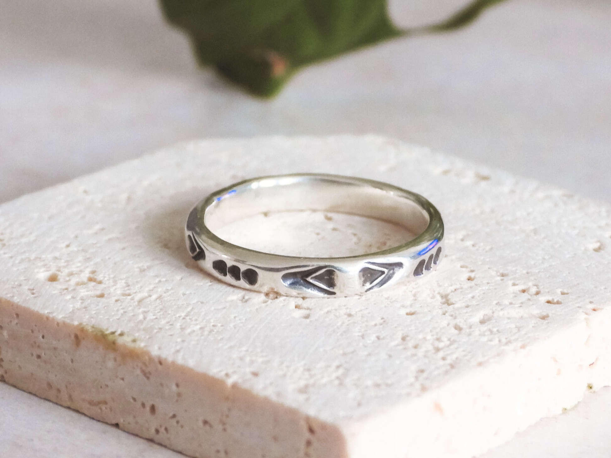 Silver ring with intricate aztec design on a light stone surface