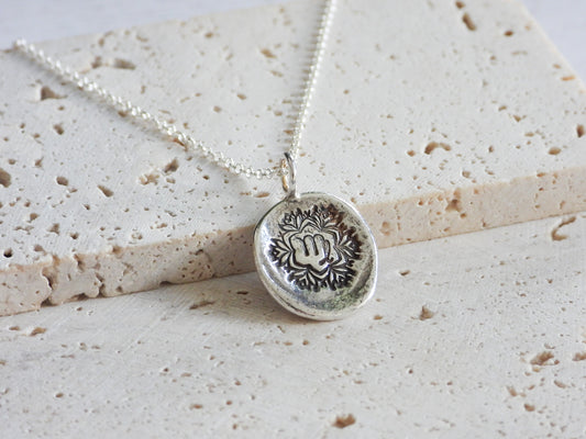 Silver virgo necklace with a round pendant on a textured beige surface