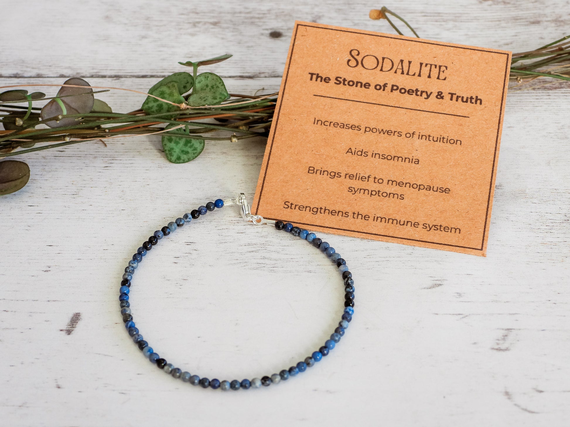 Blue sodalite beaded bracelet with a card explaining its properties on a wooden surface