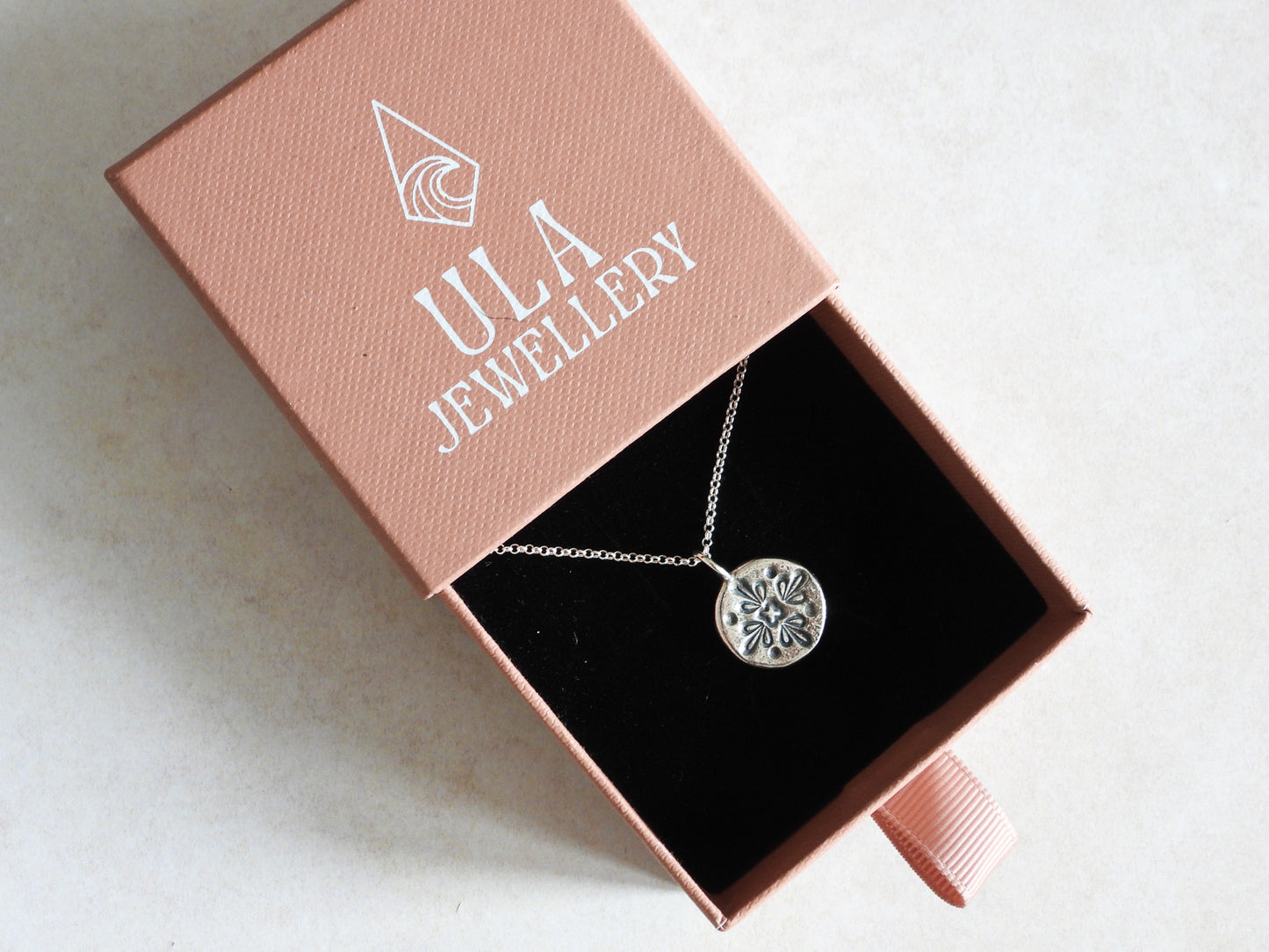 Silver necklace with a pendant in an open Ula Jewellery box on a light background